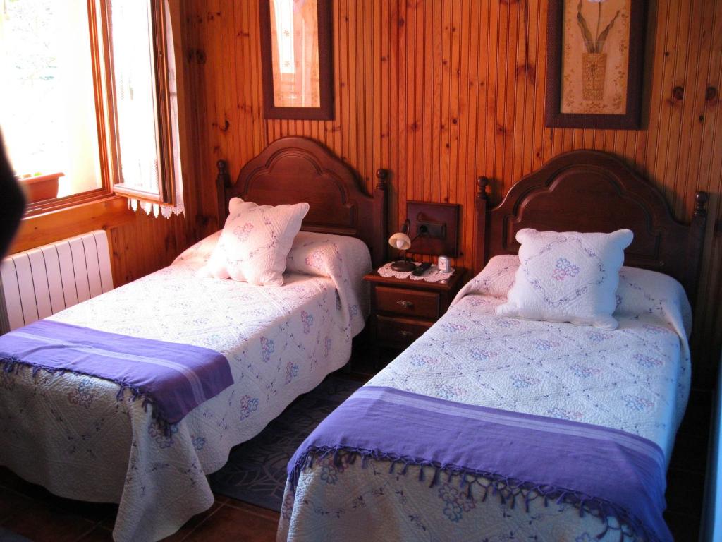 two beds in a bedroom with wooden walls at Casas Rurales La Casina in Intriago