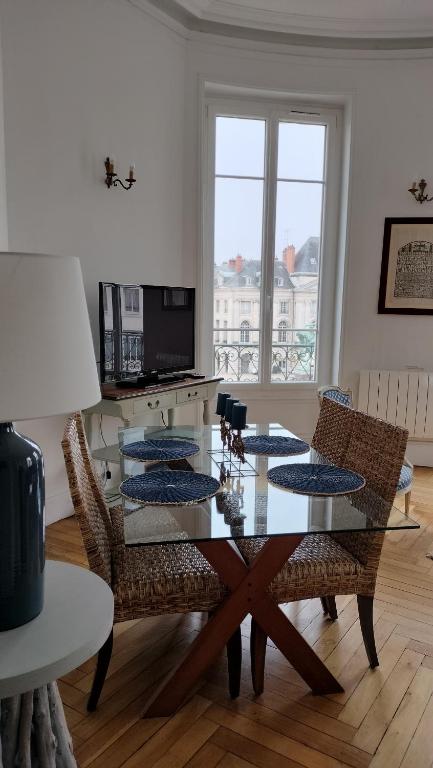 une salle à manger avec une table et des chaises en verre dans l'établissement Appartement F3 au balcon de la Place du Martroi, à Orléans