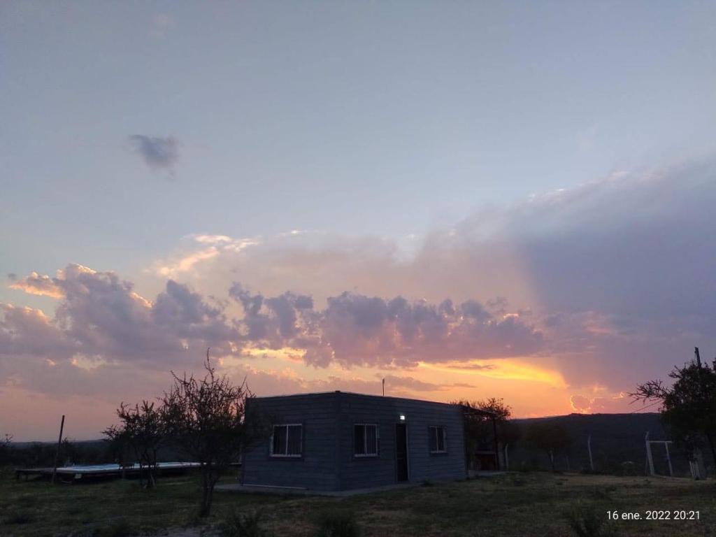ein Haus auf einem Feld mit einem Sonnenuntergang im Hintergrund in der Unterkunft Aguarà del Sol-Aguarà Guazù in Valle Hermoso