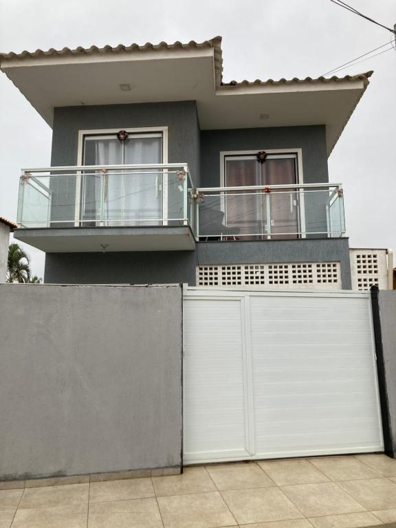 una casa con porte bianche e balcone di Casa aconchegante no Florestinha a Cabo Frio