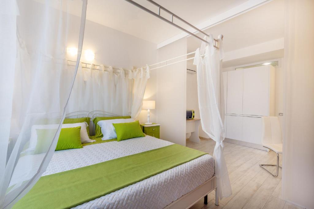 カリアリにあるSette Colli Guesthouseのベッドルーム(緑の枕と天蓋付きベッド付)