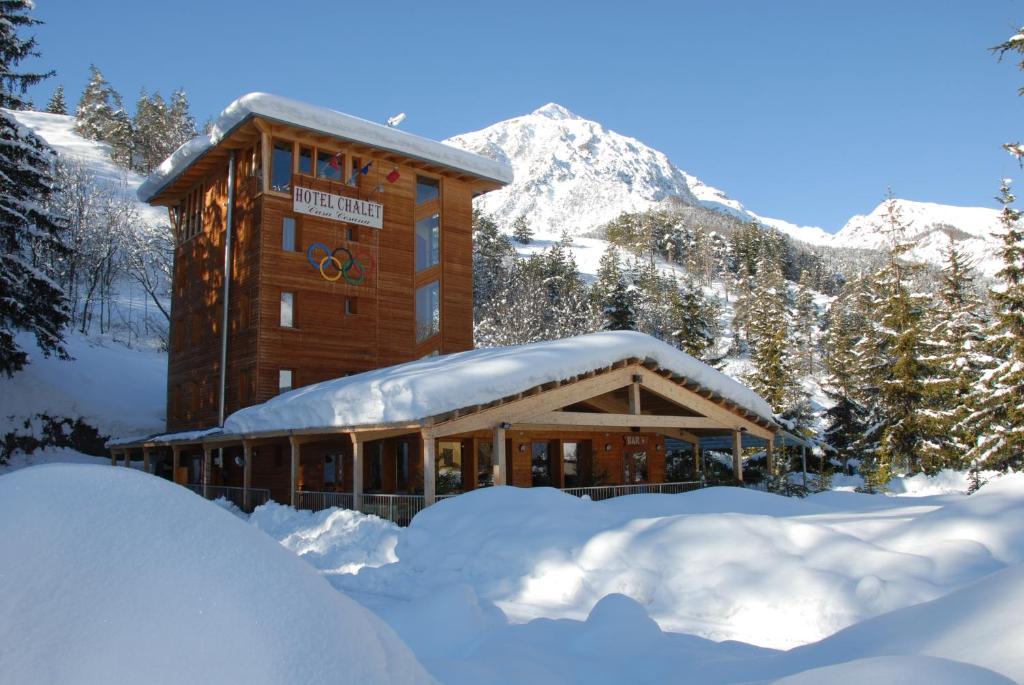 a building covered in snow in front of a mountain at Hotel Chalet Casa Cesana in Cesana Torinese