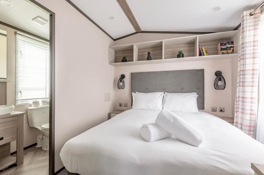 a bedroom with a large white bed and a mirror at Lodge 17 St Andrews in St. Andrews