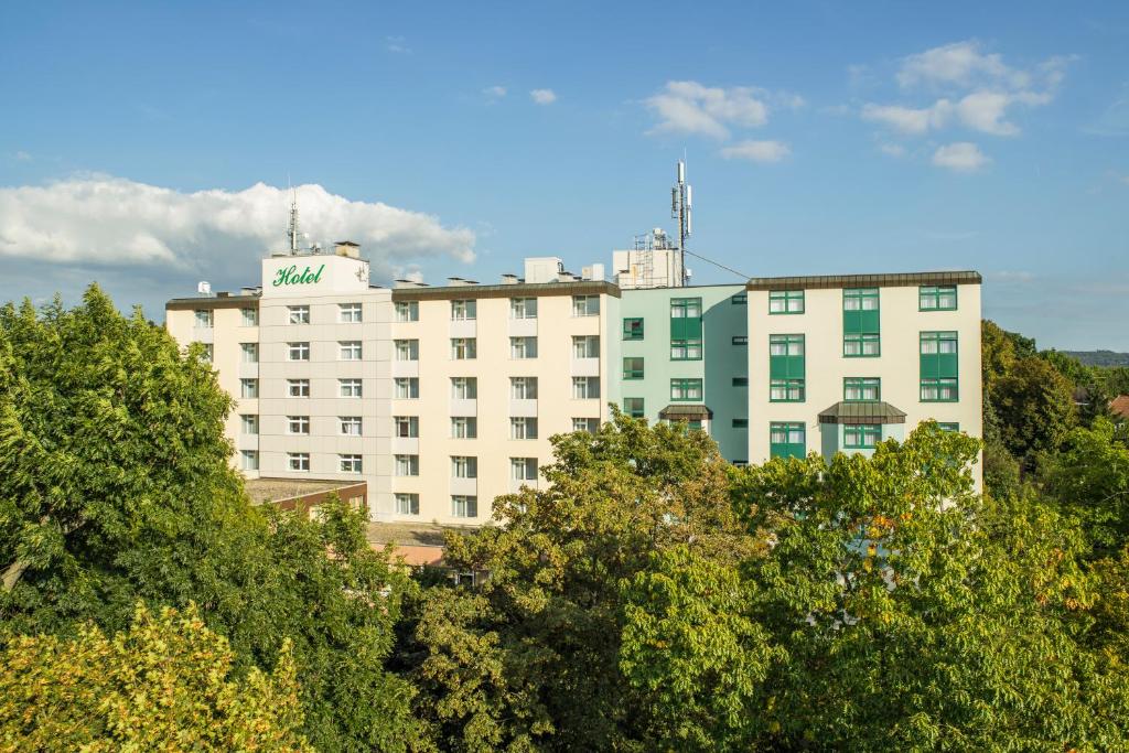 ギーセンにあるベストウエスタン プラス ホテル シュタインガルテンの目の前に木々が植えられた白い大きな建物