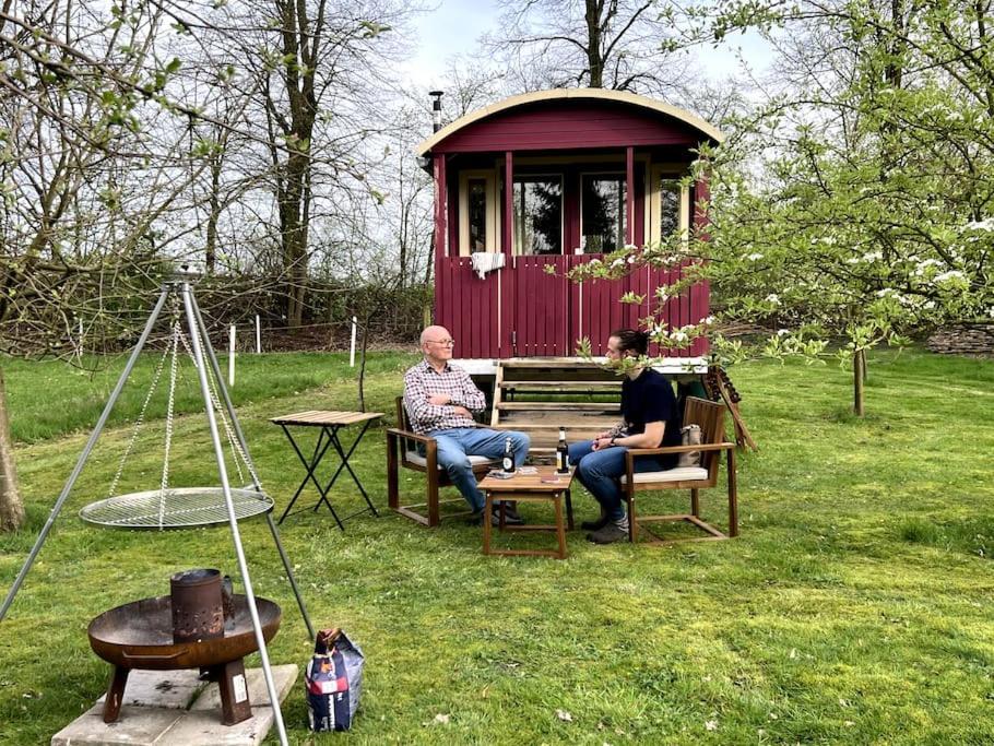 two people sitting on a bench in front of a red shed at Kuscheltage im Zirkuswagen am Kanal im Münsterland in Recke
