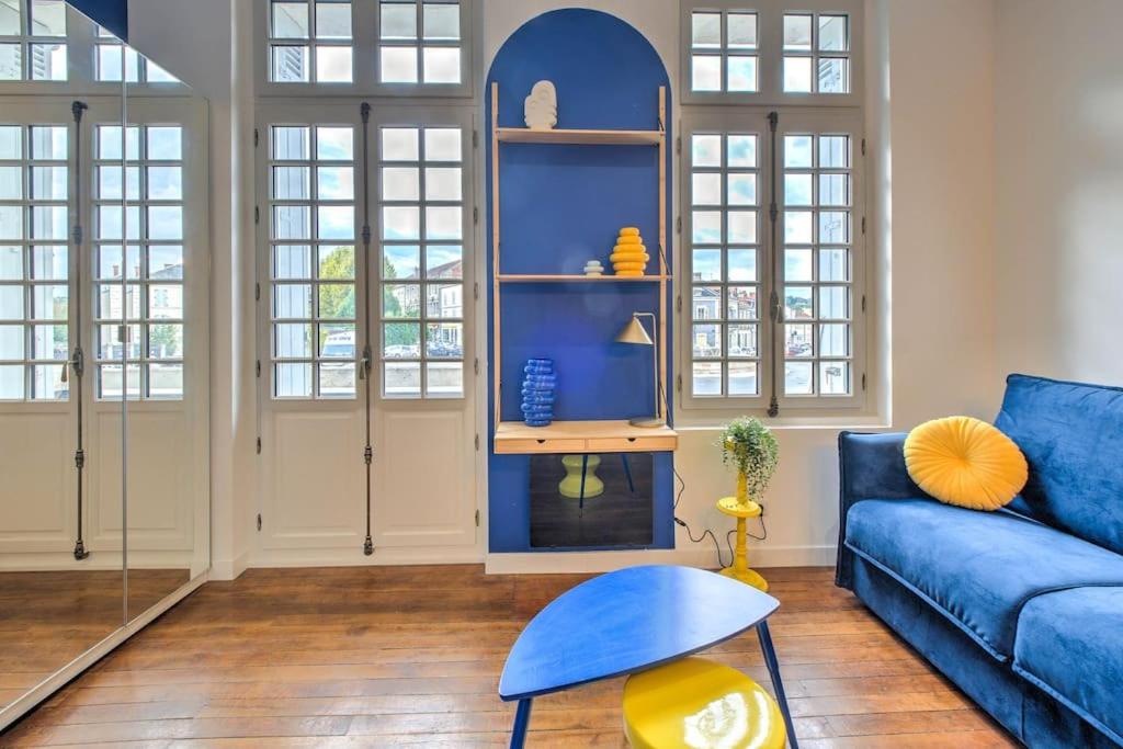 un salon avec un canapé bleu et des fenêtres dans l'établissement Chez Paulette au Petit Palais, à Périgueux