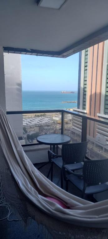 a balcony with a hammock and a table and chairs at Beira-Mar Flat Venetto - Premium in Fortaleza