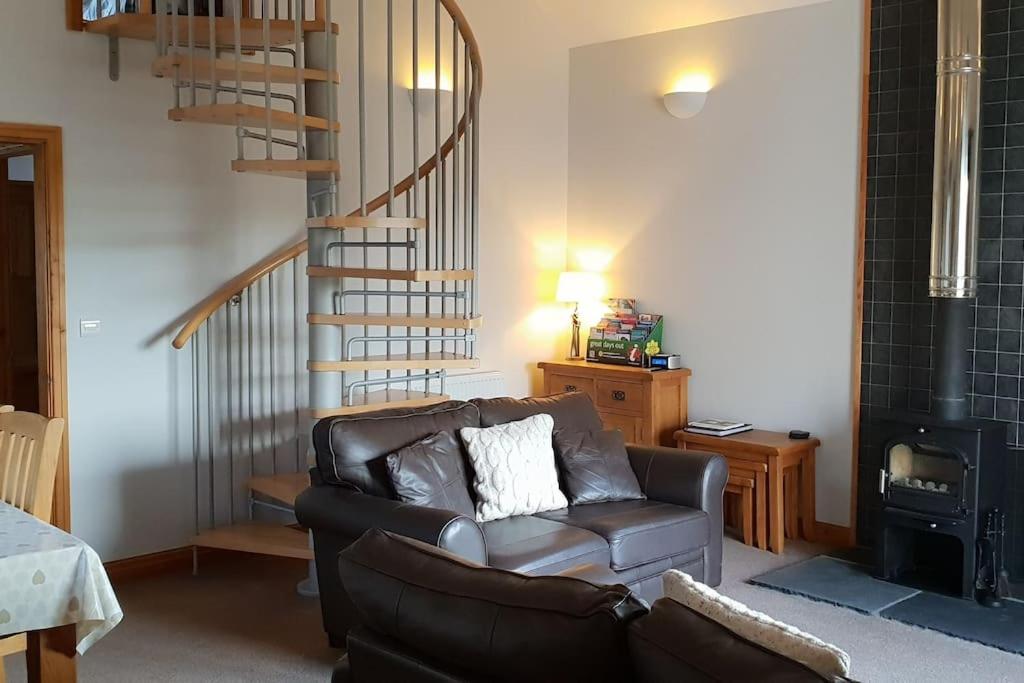 un salon avec un canapé et un escalier en colimaçon dans l'établissement Bwlch Cottage, à Gwaynynog