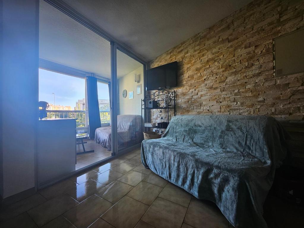 une chambre avec un lit et un mur de briques dans l'établissement Plage Sud France, au Cap d'Agde