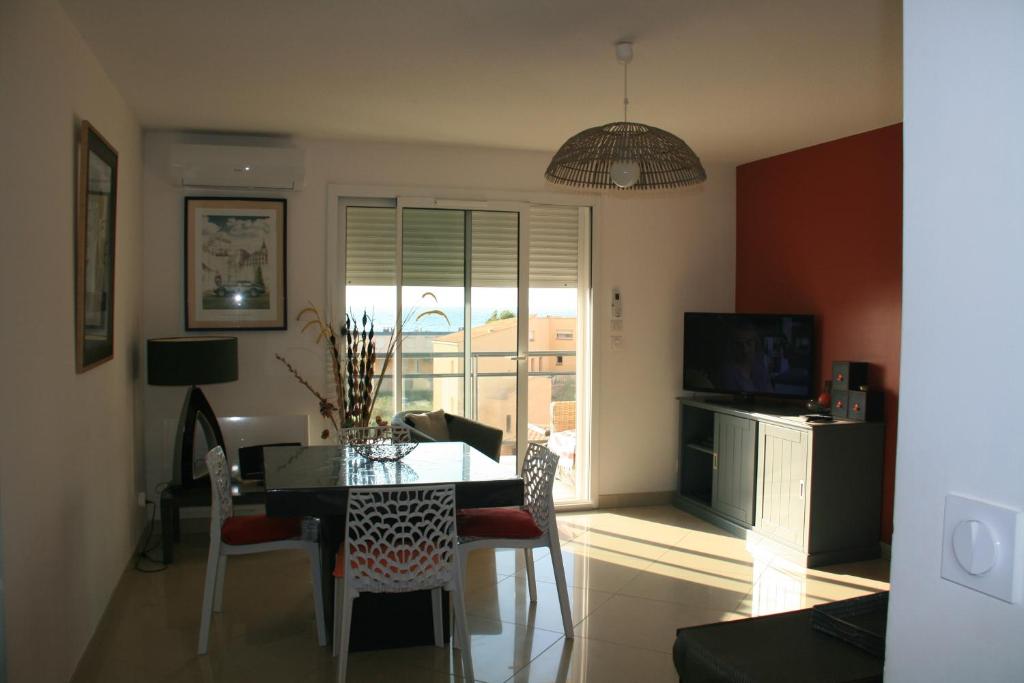 a dining room with a table and chairs and a window at T3 vue mer 100m de la plage wifi et parking in Saint Pierre La Mer