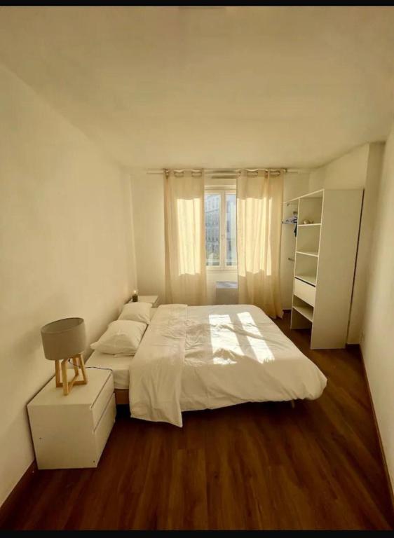 une chambre avec un grand lit blanc et une fenêtre dans l'établissement Élégance au cœur de Marseille, à Marseille