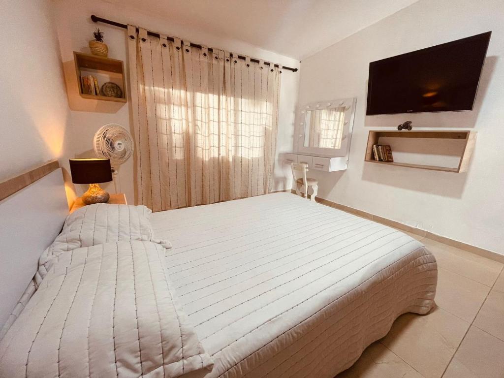 a bedroom with a white bed with a tv on the wall at Apartaestudio Los Profes in Mocoa