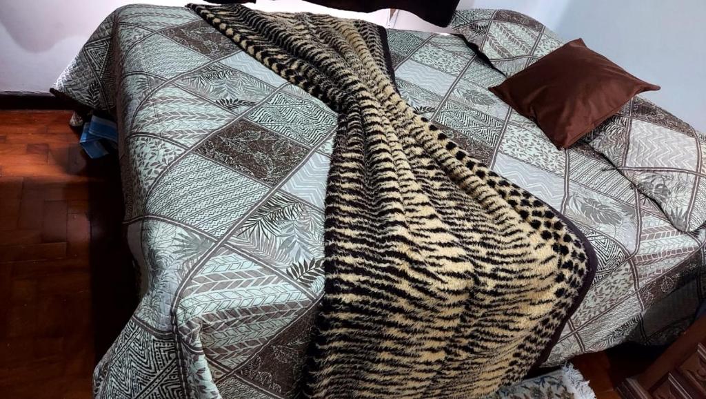 a blanket with a leopard pattern on a bed at Apartamento frente a praia Santos in Santos