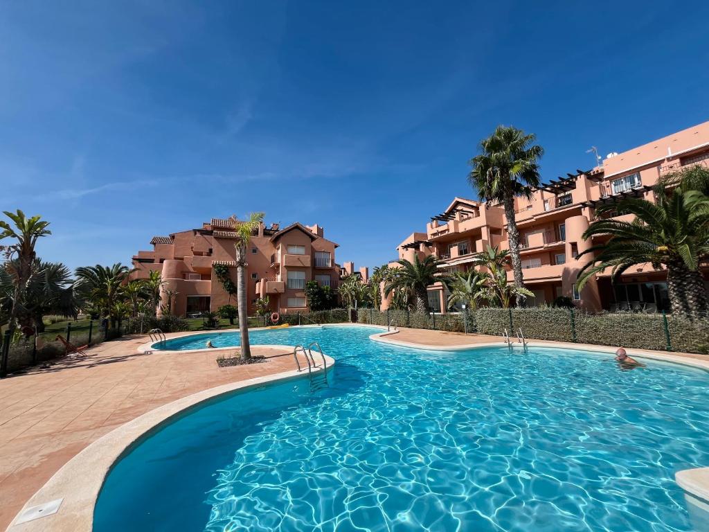 a swimming pool in a resort with palm trees and buildings at Pool, Beach and Sun in Mar Menor Golf Resort in Torre-Pacheco