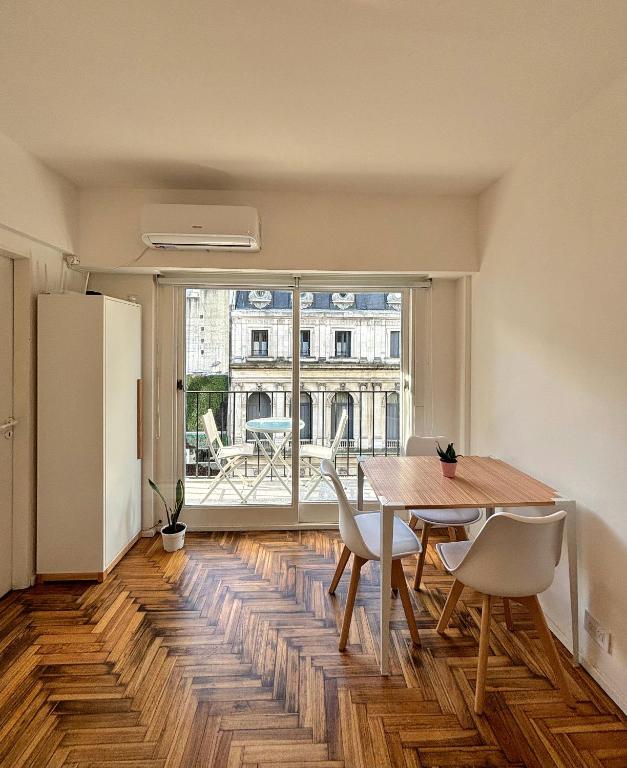 a dining room with a table and chairs and a large window at Apartamento BA Obelisco in Buenos Aires