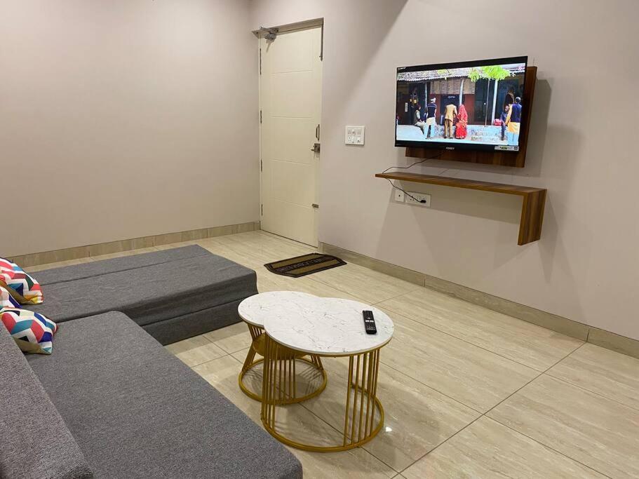 Habitación con sofá, mesa y TV. en Tara Luxury Homes 2BHK, en Solan