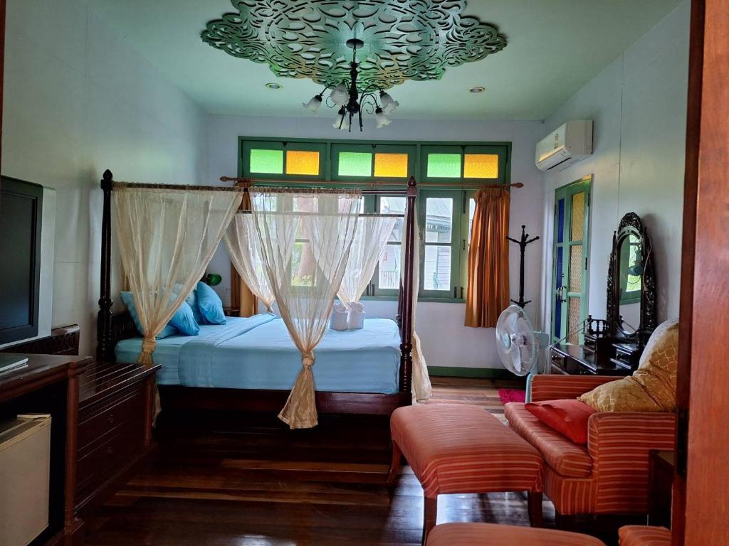 a bedroom with a canopy bed and a couch at Baanrak amphawa homestay in Amphawa