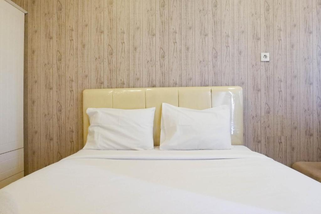スラバヤにあるSimply Modern Studio at Pavilion Permata Apartment By Travelioの部屋にある白いシーツと枕が置かれたベッド