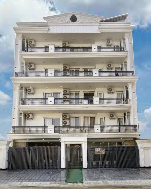 a large white building with balconies and a fence at Miyabi suites in Gurgaon