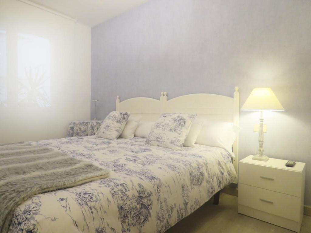 1 dormitorio con cama y mesita de noche con lámpara en Pension Mayte, en Pamplona