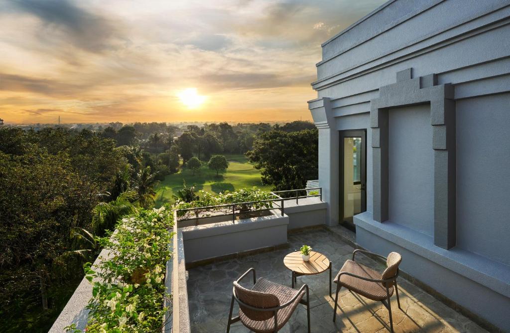 a balcony with a table and chairs and the sunset at Hyatt Regency Yogyakarta in Yogyakarta