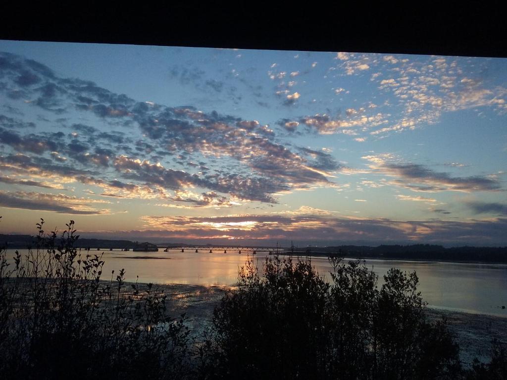 un coucher de soleil sur une masse d'eau avec des nuages dans l'établissement Bay Bridge Motel, à North Bend