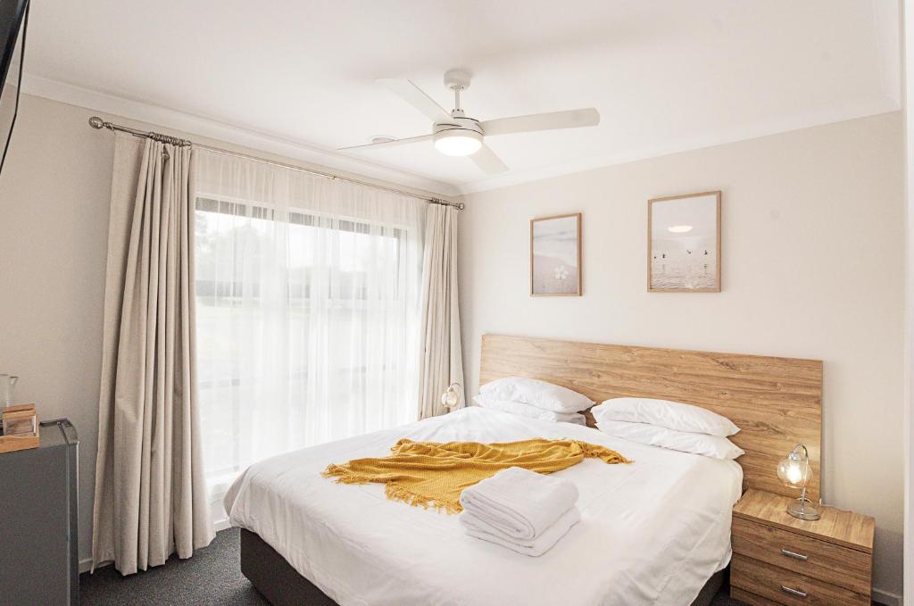 a bedroom with a bed with white sheets and a window at Morview Holiday Homes-Giraffe in Hamilton
