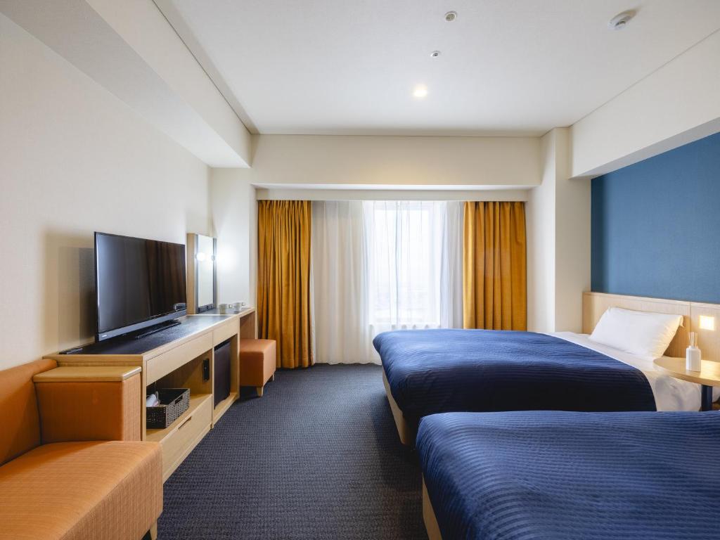 a hotel room with two beds and a flat screen tv at Kansai Airport Washington Hotel in Izumi-Sano