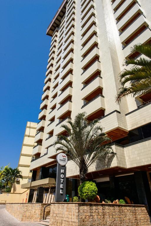 Un edificio alto con un cartel delante. en SAN MARINO SUITES HOTEL By NOBILE, en Goiânia