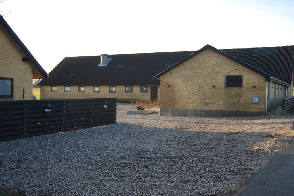 a barn with a fence in front of a building at Rind B&B in Herning