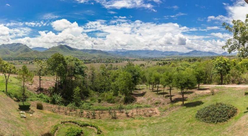 Una vista aérea de un campo con árboles y montañas. en Feel good, en Pai