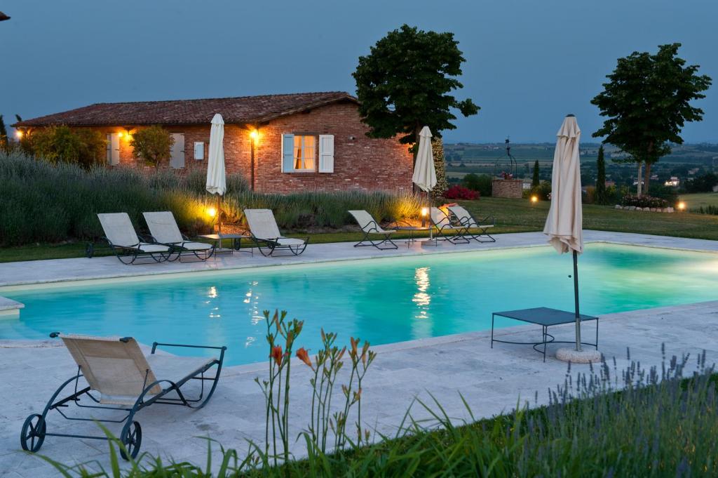 a pool with chairs and umbrellas in front of a house at Casa Vacanze B&B Poggio Al Vento Toscana in Foiano della Chiana