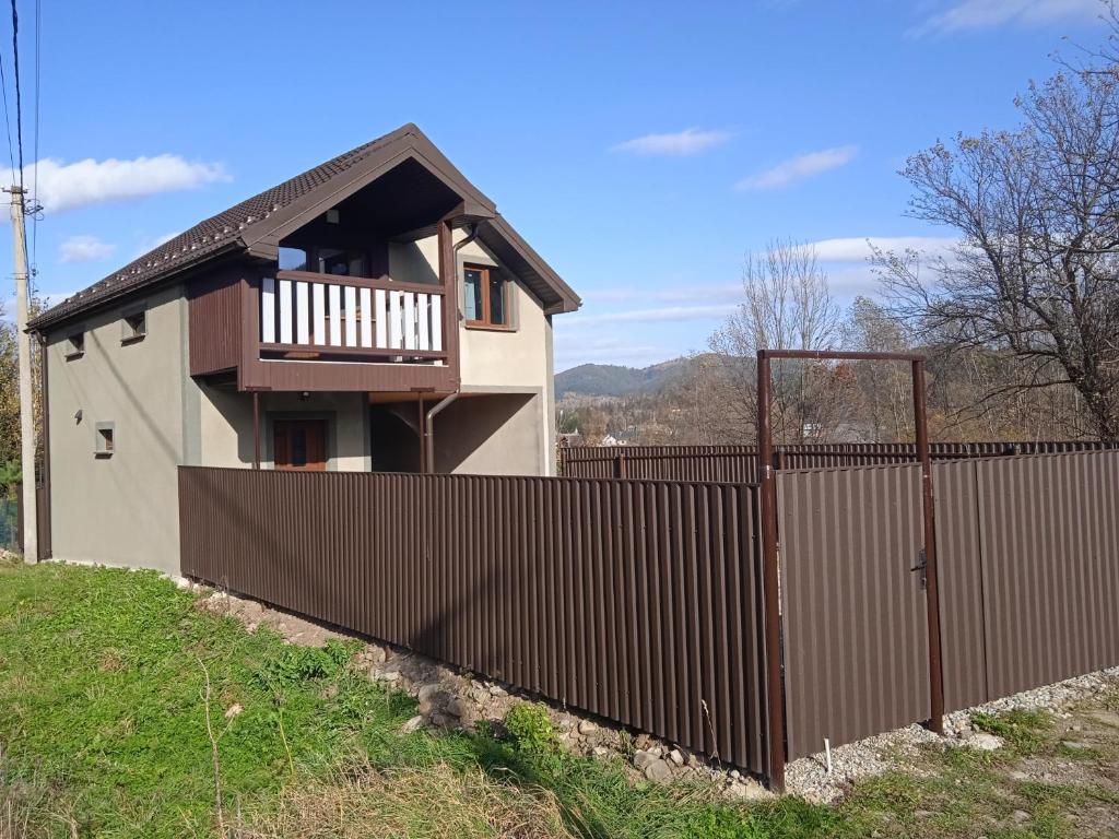a house behind a fence with a wooden gate at Галерея Карпат in Mykulychyn