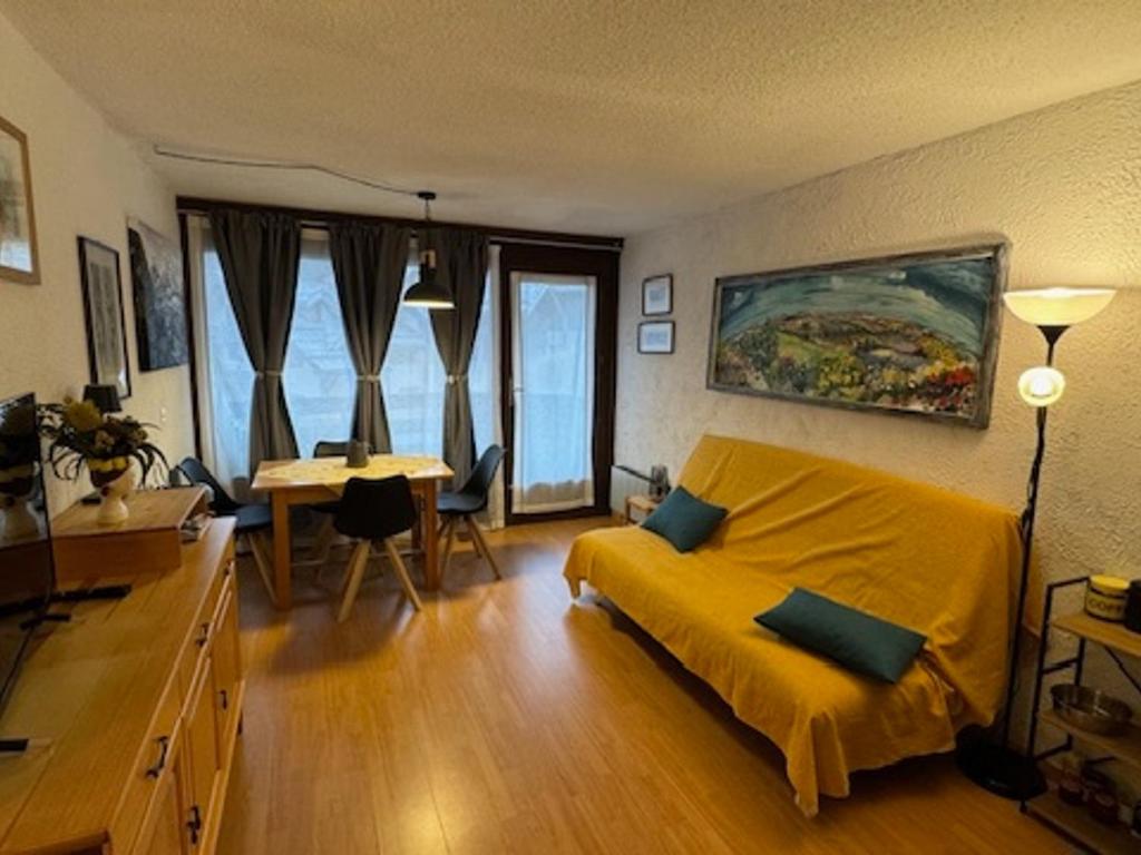 - une chambre avec un lit jaune, un bureau et une table dans l'établissement Studio charmant proche pistes et commerces avec parking, balcon, animaux acceptés - FR-1-445-210, à Montgenèvre