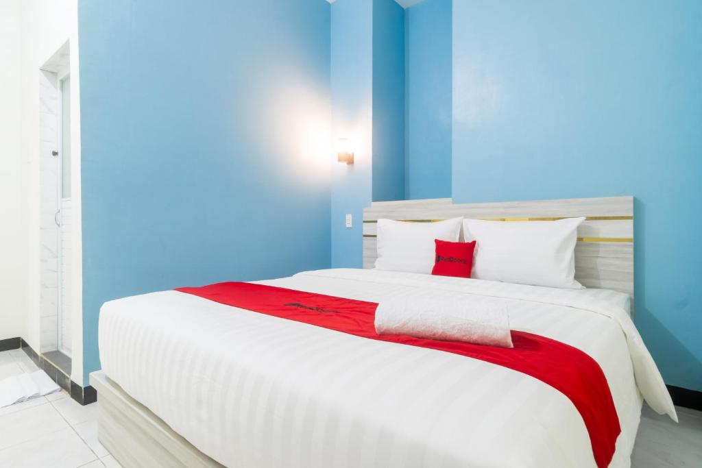 a bedroom with a large white bed with red accents at RedDoorz Plus at Sempurna Inn Medan in Polonia Airport