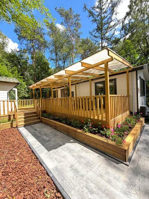 a house with a wooden deck with a woodenvisor at Bosrijk chalet Veranda, Honden in Doornspijk