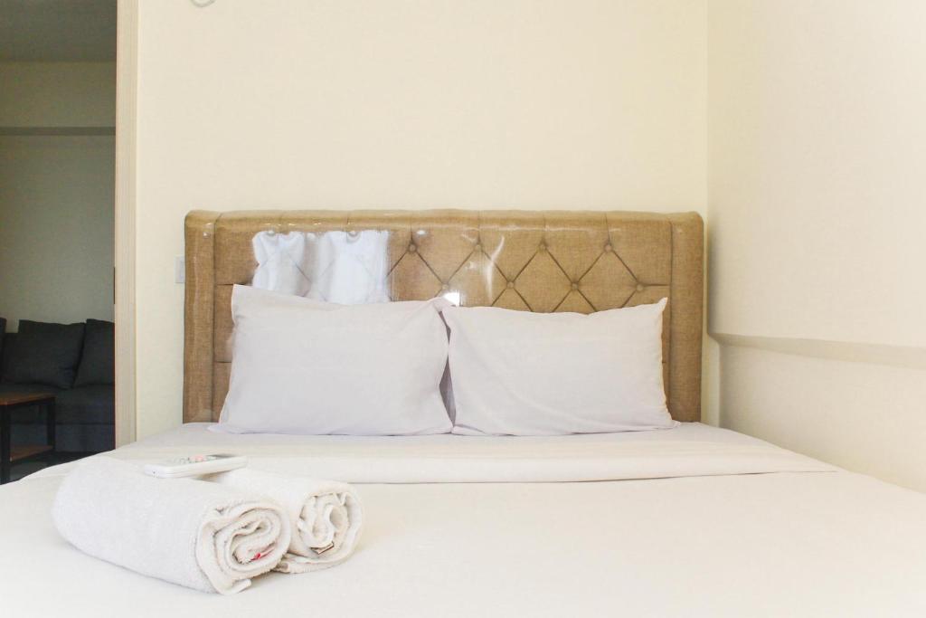 ein Bett mit weißen Kissen und Handtüchern darauf in der Unterkunft Comfortable and Homey 3BR at Meikarta Apartment By Travelio in Cikarang