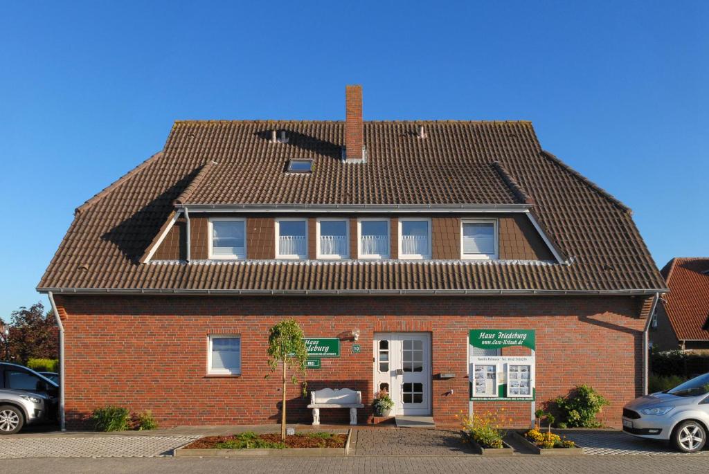 ein rotes Backsteinhaus mit einem schwarzen Dach in der Unterkunft Ferienwohnungen im Haus Friedeburg in Carolinensiel