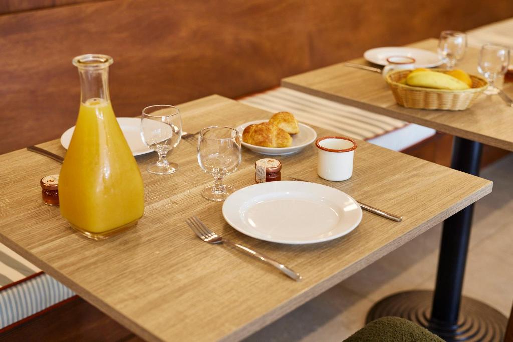 a wooden table with plates of food and a bottle of orange juice at Hotel des Victoires - Restaurant in Cannes