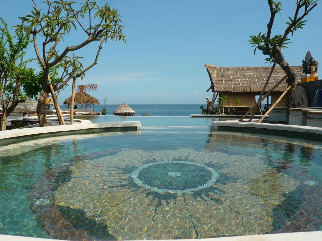 einen Pool in einem Resort mit dem Meer im Hintergrund in der Unterkunft Classic Beach Villas in Amed