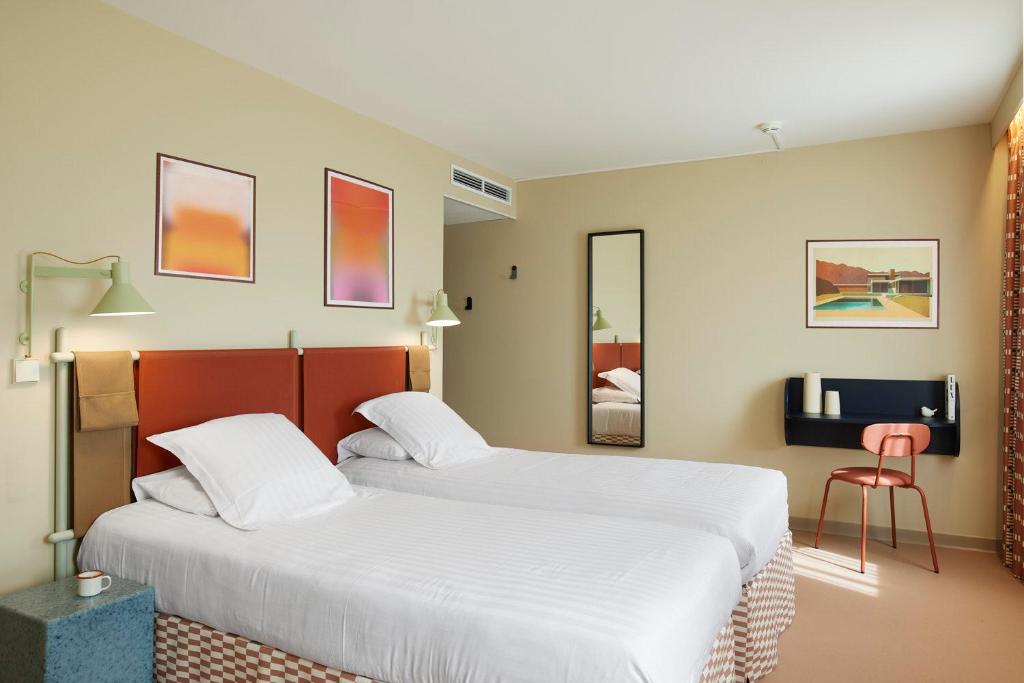 a hotel room with two beds and a tv at Hotel des Victoires - Restaurant in Cannes