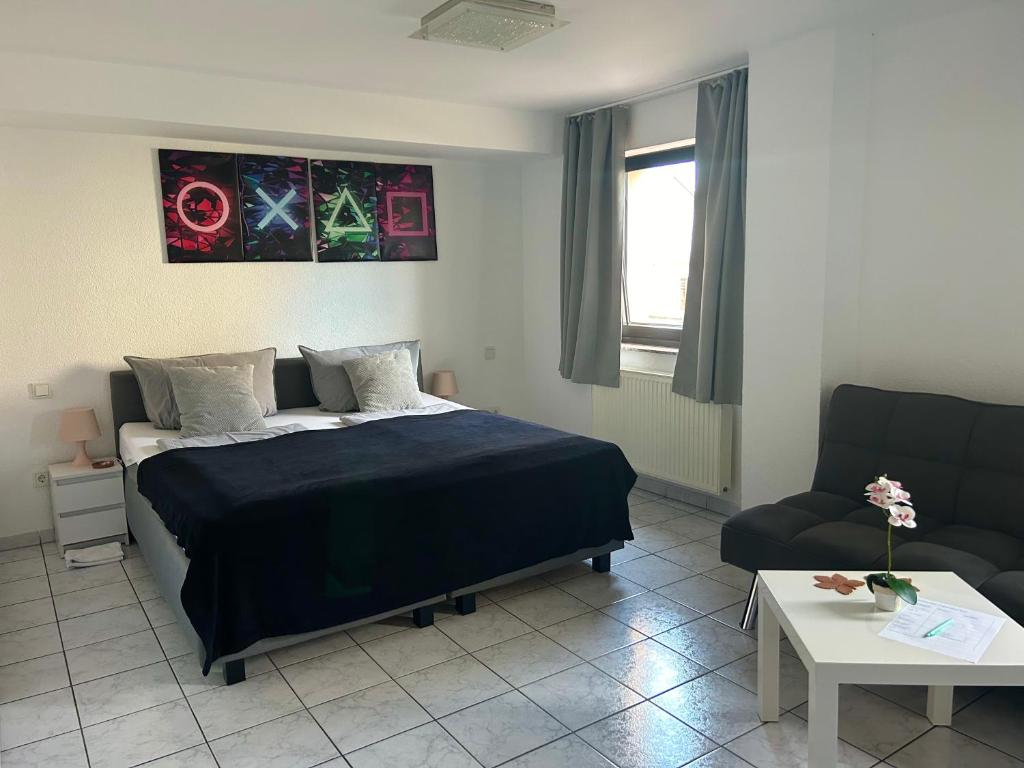 ein Schlafzimmer mit einem Bett, einer Couch und einem Tisch in der Unterkunft Mikroapartments Klarenthal in Saarbrücken