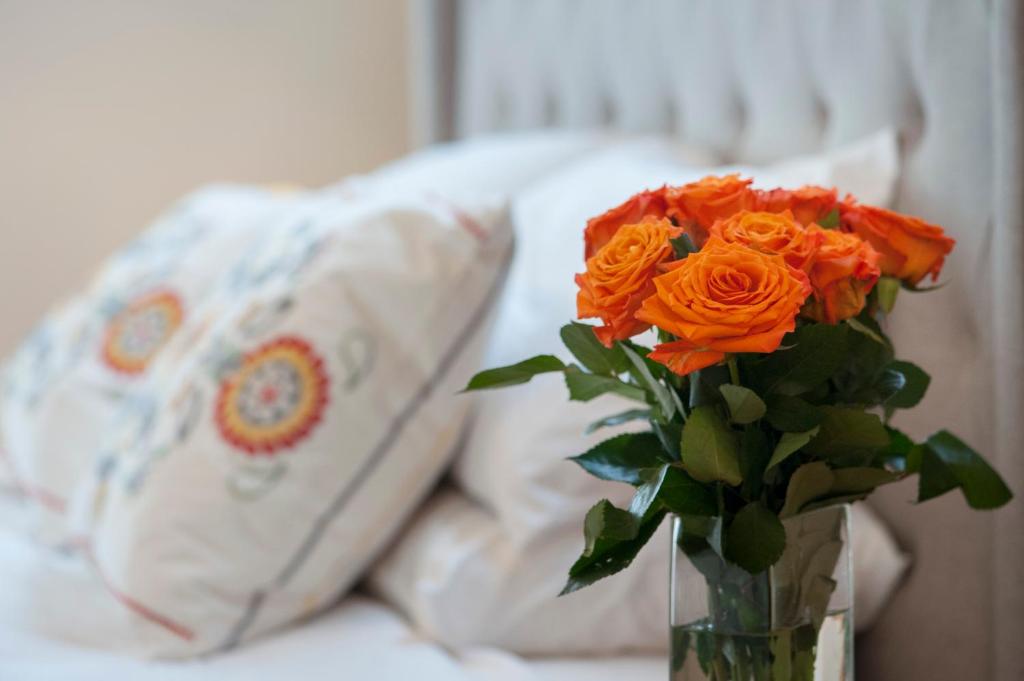 a vase filled with orange roses sitting on a bed at The Nest at Gundaroo in Gundaroo
