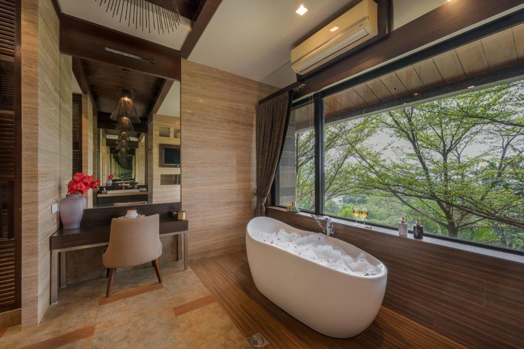 a bathroom with a tub and a desk and a window at SaffronStays Rockford Manor in Āmbavna