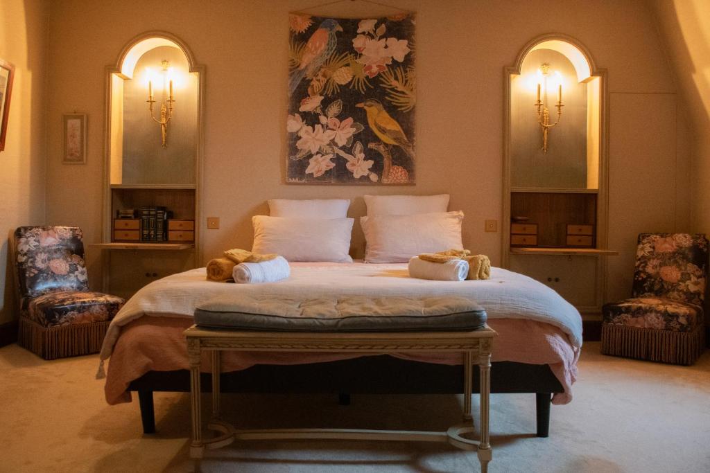 a bedroom with a large bed with two chairs at Les Jardins de la Beylie - Chambre d'hôtes in Preyssac-dʼAgonac