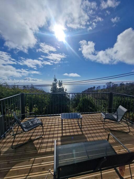 two chairs and a table on a wooden deck at Casa Vieira in Fajã da Ovelha