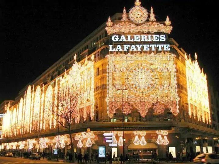 un grand bâtiment avec des lumières allumées la nuit dans l'établissement Bed setting room in Galeries Lafayette street, à Paris