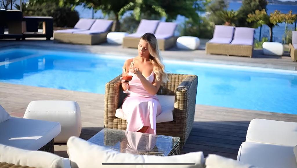 a woman sitting in a chair next to a pool at Résidence Aigue Marine in Coti-Chiavari