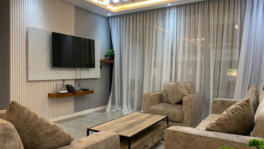 a living room with a tv and two chairs and a table at Premium appart avec piscine et vue sur la ville in Yaoundé