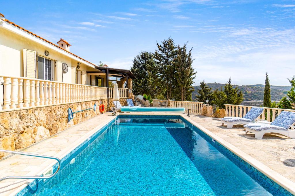 una piscina con dos sillas y una casa en Villa Aris by Ezoria Villas, en Tsadha